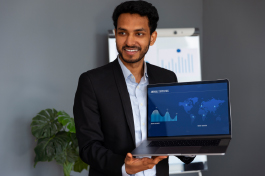 Smiling student presenting laptop screen with financial data, representing the Best College for Financial Accounting courses.