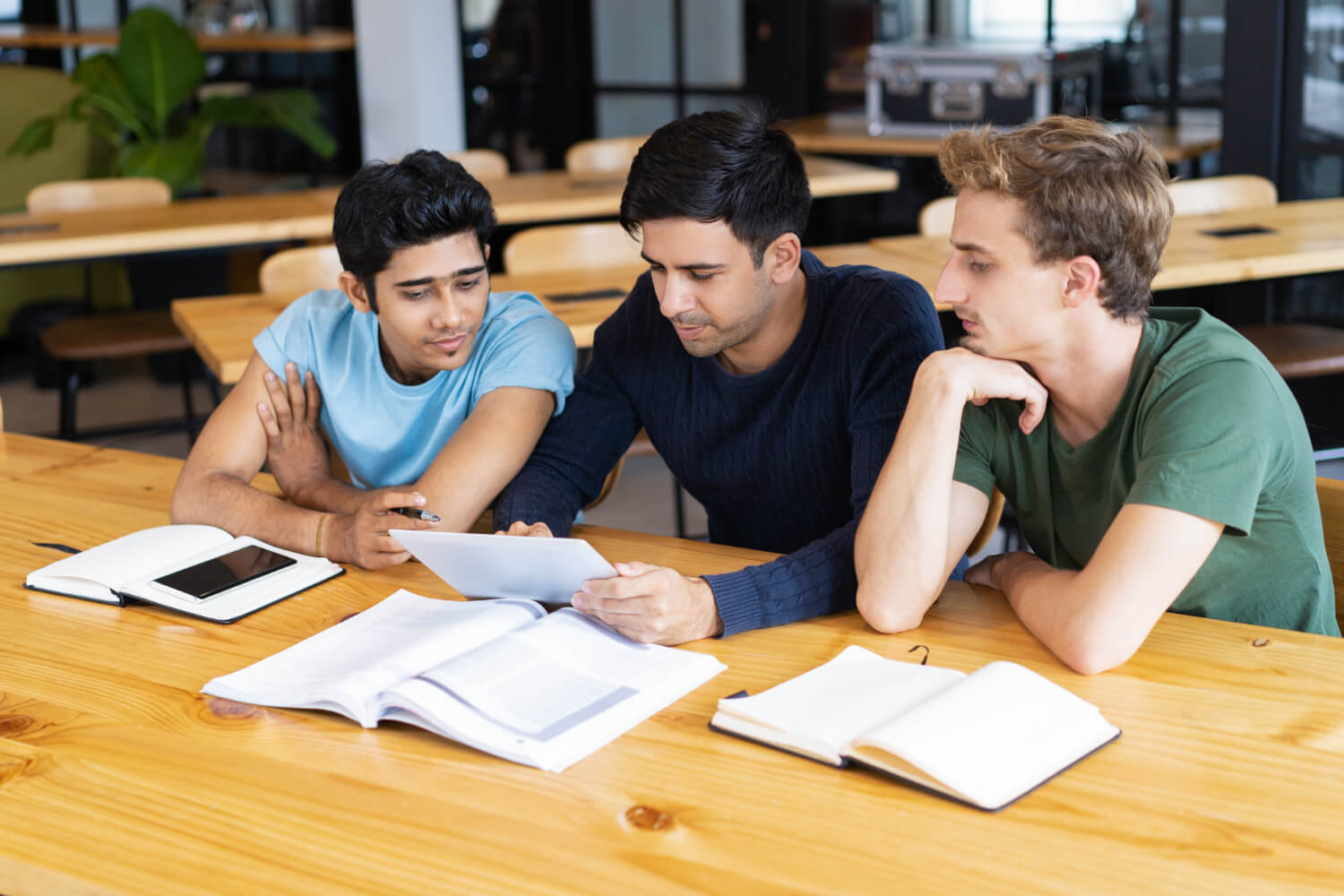 Three students reviewing documents together in a study environment, symbolizing teamwork and clarity in the Admission Procedure.